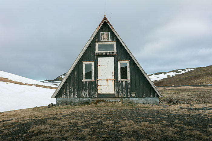 A-frame tiny home on a grassy landscape with cloudy sky, highlighting considerations in tiny home purchasing.