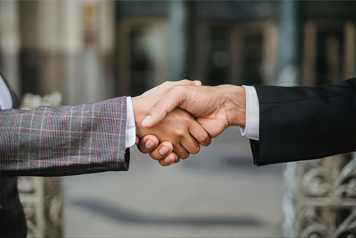 Two people in business attire shaking hands, symbolizing a transaction or agreement in the tiny home market.