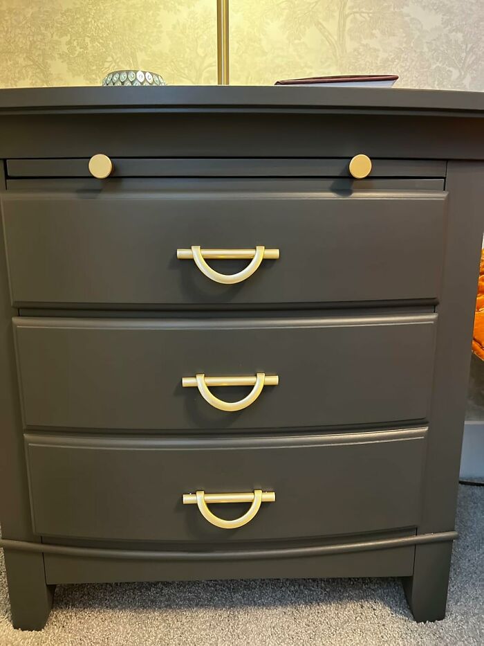 Modern dark dresser with stylish gold handles and decor, updating apartment aesthetics.