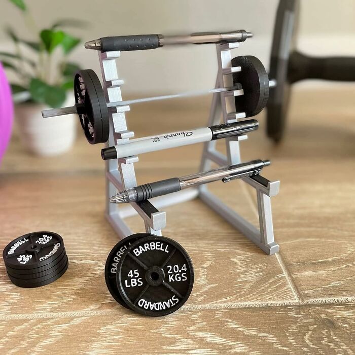 Fun office supplies: a miniature barbell rack holding pens, creating a playful workspace atmosphere.