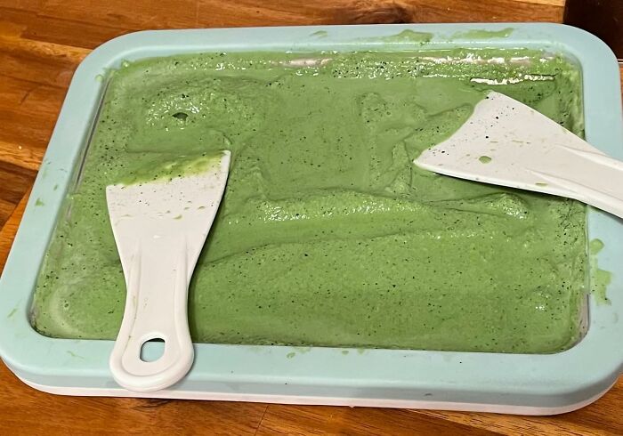 Green mixture spread in a tray with two white spatulas; a borderline genius kitchen tool.