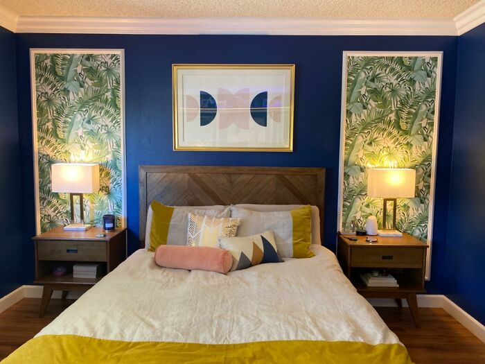 Modernized bedroom with bold blue walls, green leaf wallpaper accents, and stylish decor.