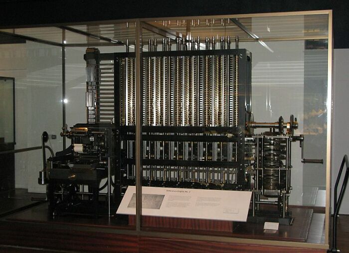 Historical invention, an early computing machine in a museum display, showcasing complex mechanisms and gears.