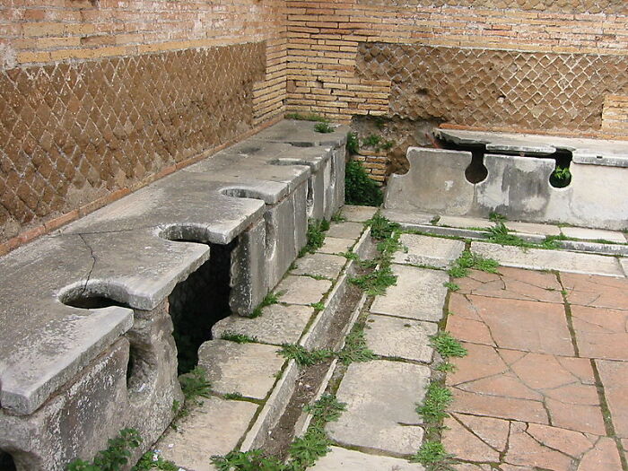 Ancient Roman public toilets showcasing historical inventions ahead of their time.