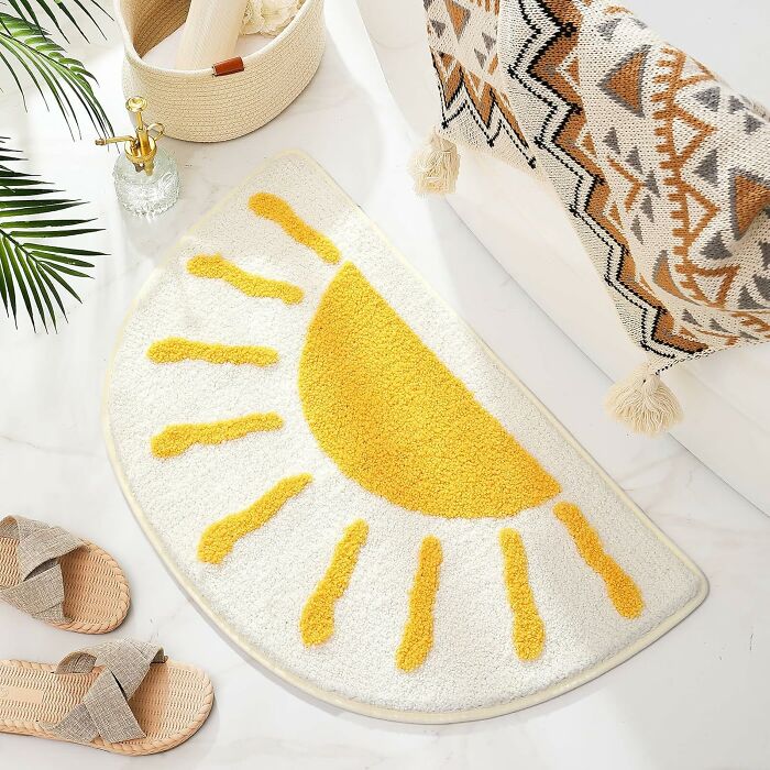 Renter friendly upgrades with a sun-patterned bath mat, decorative blanket, and woven sandals on a marble floor.