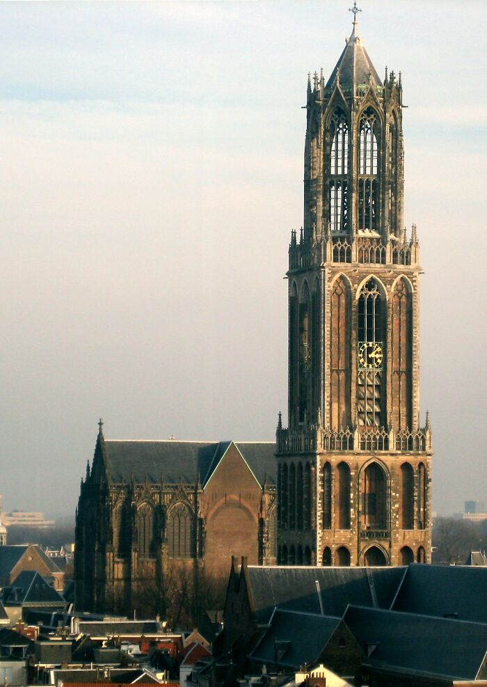 Tall, historic church tower against a soft sky, showcasing intricate architectural details and fascinating design.