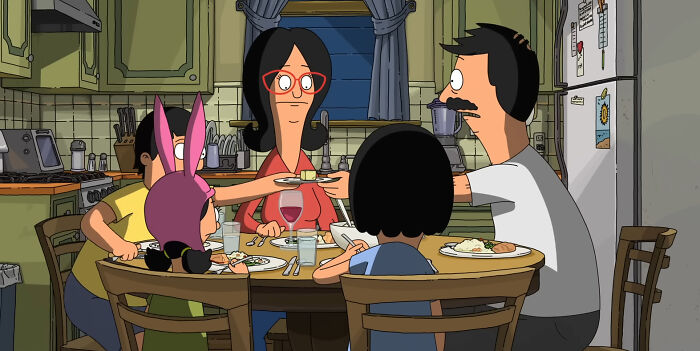 Animated family enjoying dinner in a cozy kitchen, from a beloved comedy series.