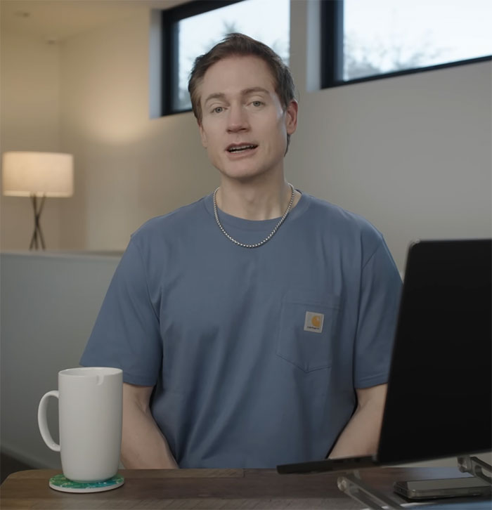 Billionaire in blue shirt discusses reversing aging in a modern office setting.