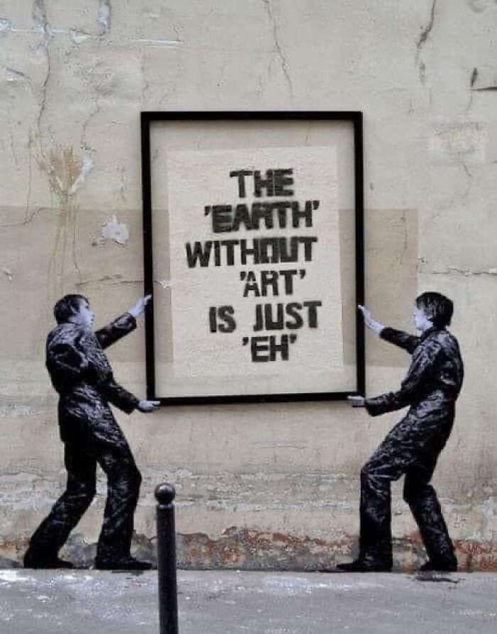 Street art of two men holding a frame with text: "The 'Earth' without 'Art' is just 'Eh'." Linguistic meme humor.