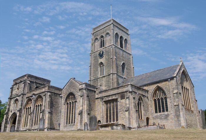 Historic stone church with tall clock tower under a clear blue sky.