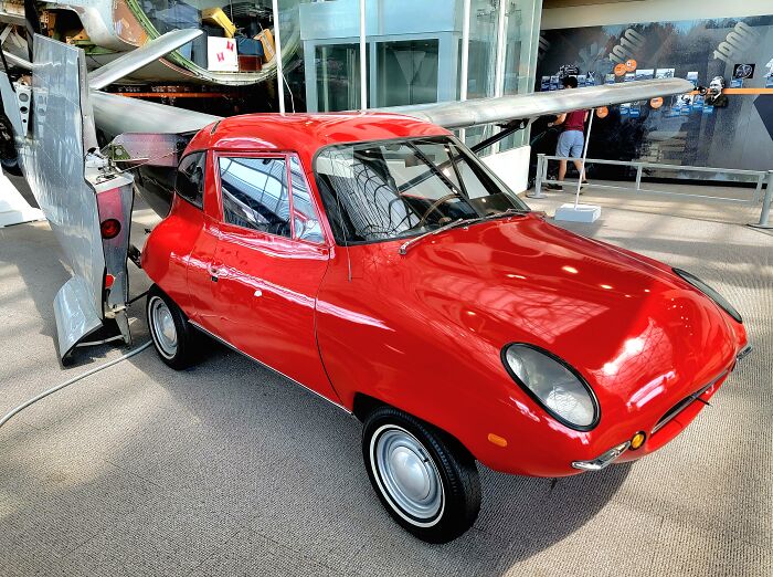 Red retro car invention displayed in a museum, showcasing historical innovations.