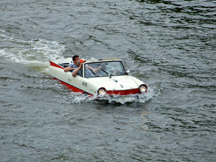 Amphibious car driving through water, showcasing historical inventions ahead of their time.