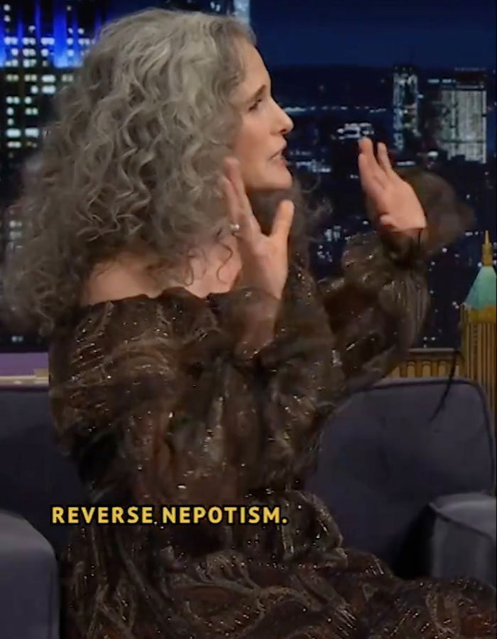 Person on a talk show discussing reverse nepotism, gesturing passionately while seated on a sofa.