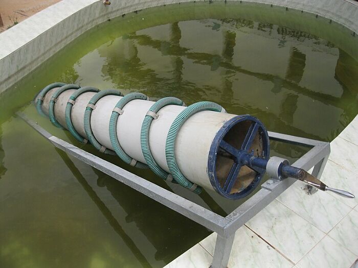 Spiral water pump, an early invention, submerged in a pond for historical engineering demonstration.