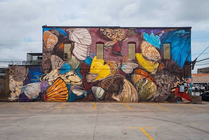 Hyper-realistic mural of butterflies painted on a building wall by a French artist.