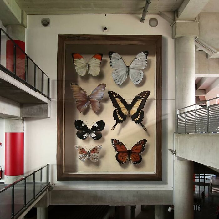 Hyper-realistic mural of butterflies by French artist, showcasing stunning lifelike details on a large indoor display.