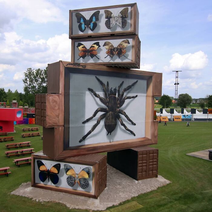 Hyper-realistic mural of butterflies and a spider painted by a French artist on stacked boxes in an outdoor setting.