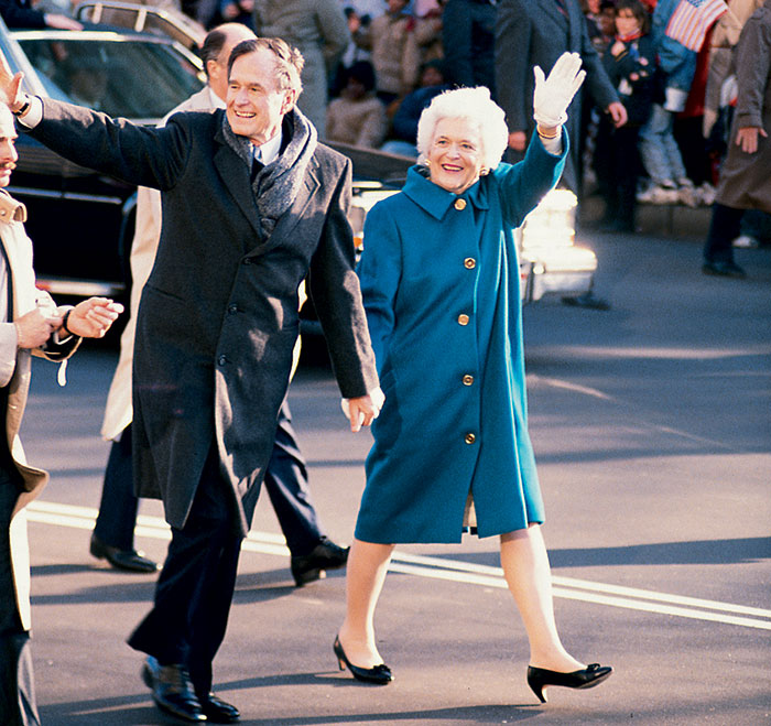 Man and woman waving during an inauguration event, showcasing past first lady's outfit.