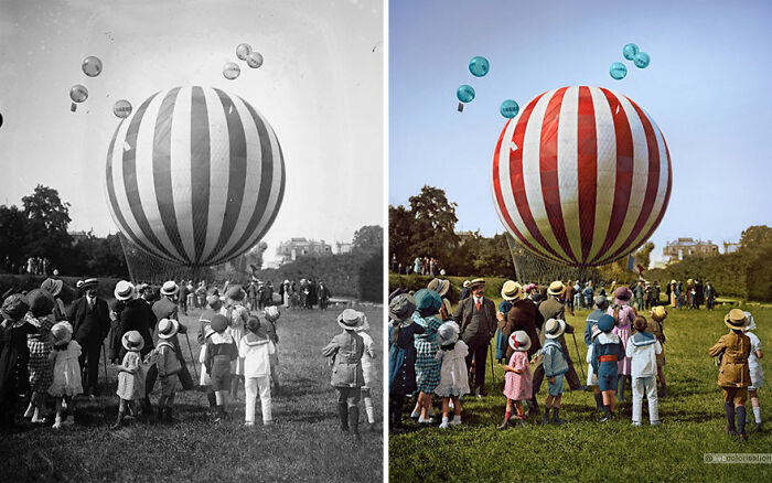 Colorized vintage photo of a striped hot air balloon with a crowd of people and children in a grassy field.