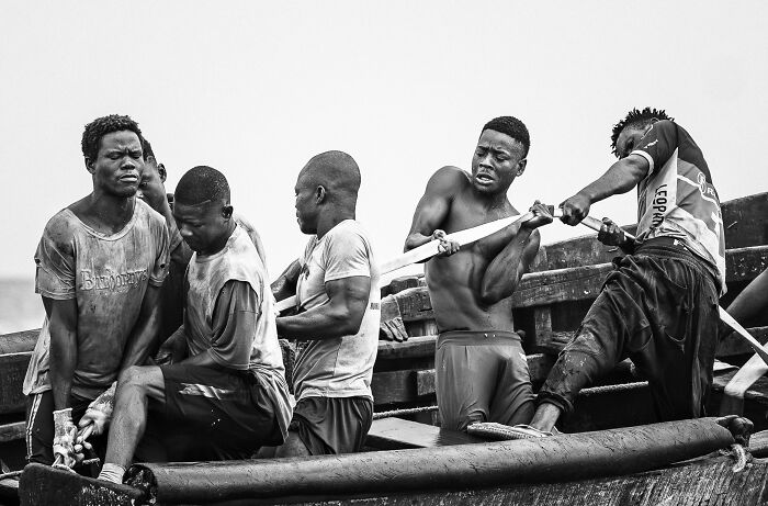 Group of men intensely rowing, showcasing teamwork; a winning photograph from the Budapest International Foto Awards.