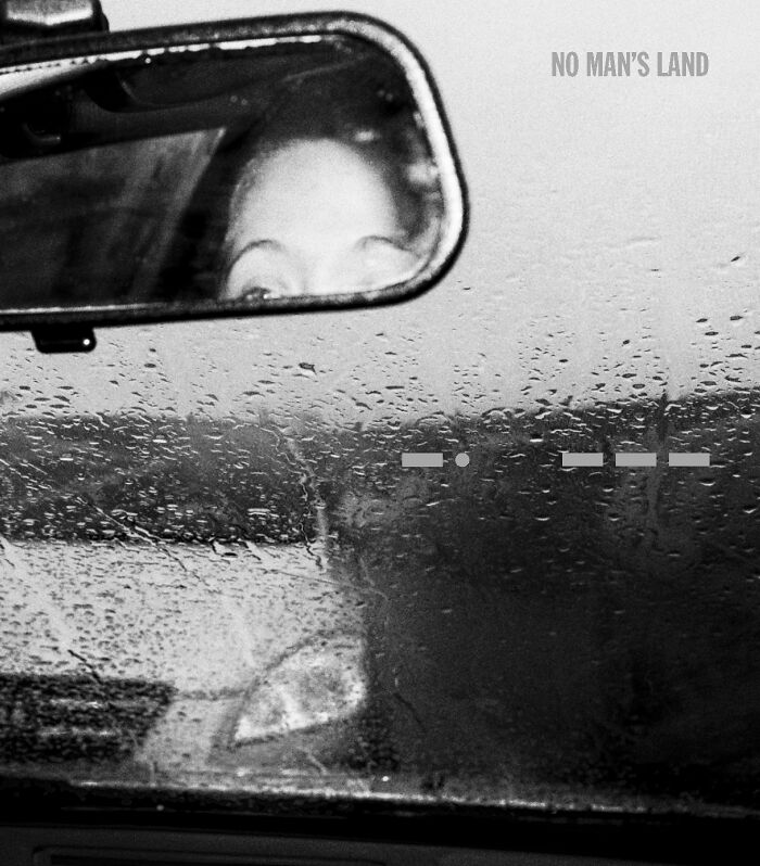 Black and white photo submission in Budapest Foto Awards, showing a woman's eyes in a rearview mirror on a rainy day.