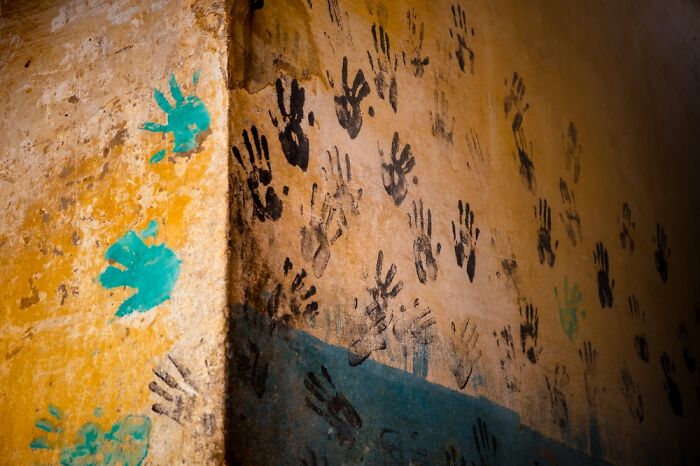 Handprints in green and black on a textured wall, showcasing creative photography at the Budapest International Foto Awards.