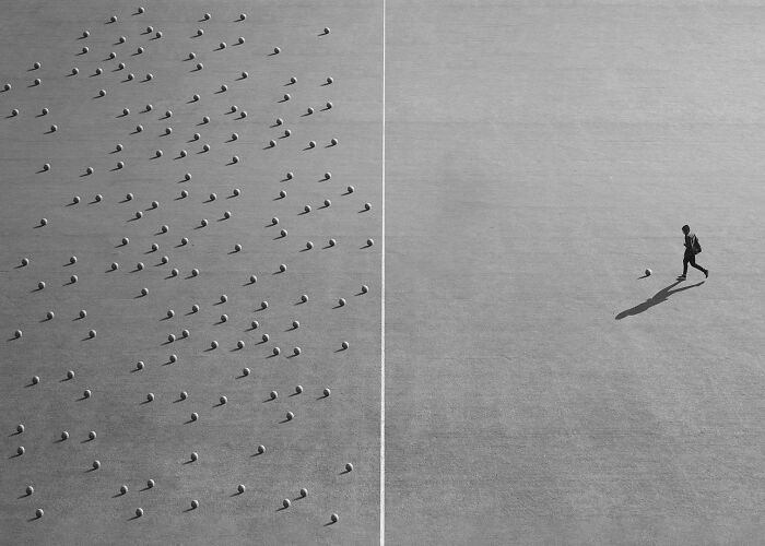 Award-winning photo from Budapest International Foto Awards, depicting a person walking past numerous scattered objects.