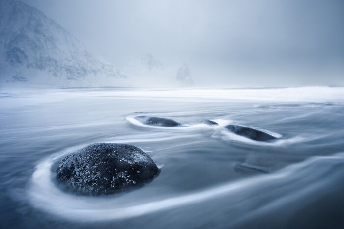 Misty seascape with smooth rocks and soft water, capturing Budapest International Foto Awards' serene winning entry.