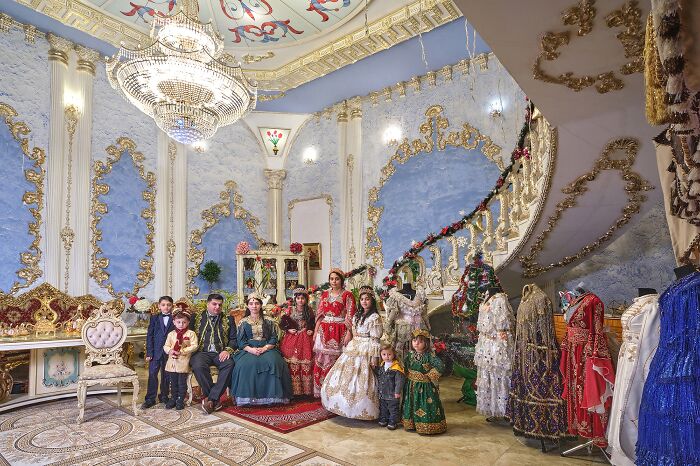 Group in ornate costumes posed in luxurious room, part of Budapest International Foto Awards 2024 winners.