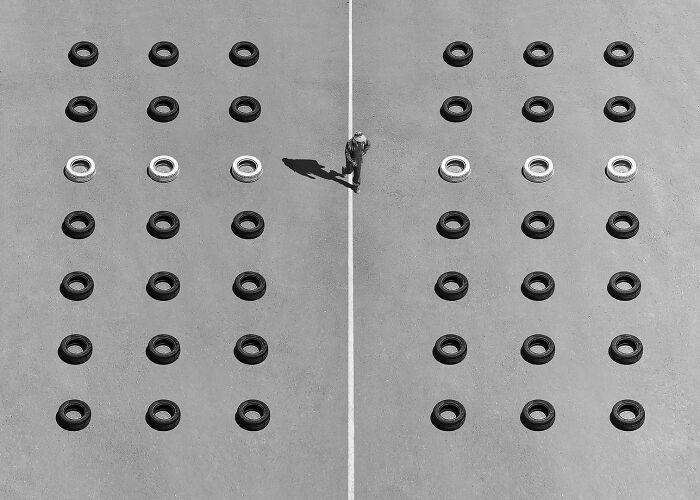 Budapest International Foto Awards winner, aerial view of symmetry with a person walking among arranged black and white tires.