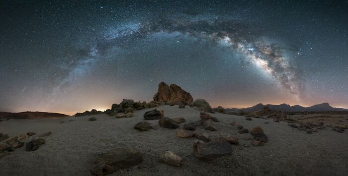 Starry sky over a rocky desert landscape at night, featuring the Milky Way, from Budapest International Foto Awards.