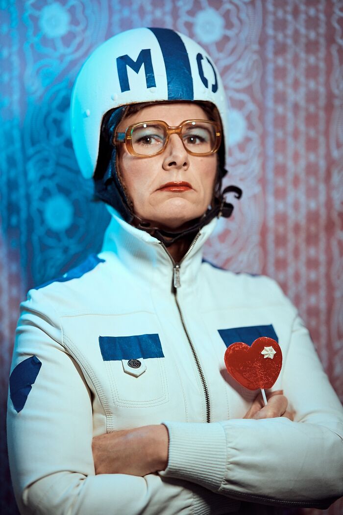 Woman in a white and blue outfit with helmet, holding a heart-shaped lollipop; winning photo from Budapest International Foto Awards.