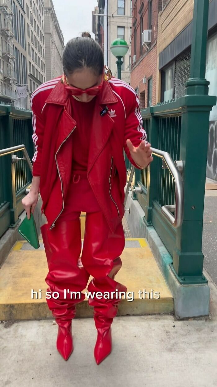 NYC local in vibrant red outfit with oversized shades, showcasing bold fashion in New York City's urban setting.