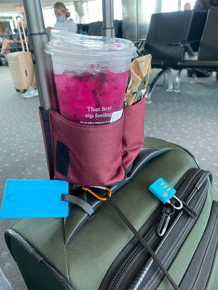 Beverage cup in a suitcase holder at the airport, highlighting travel convenience for Less-Mess-2025.