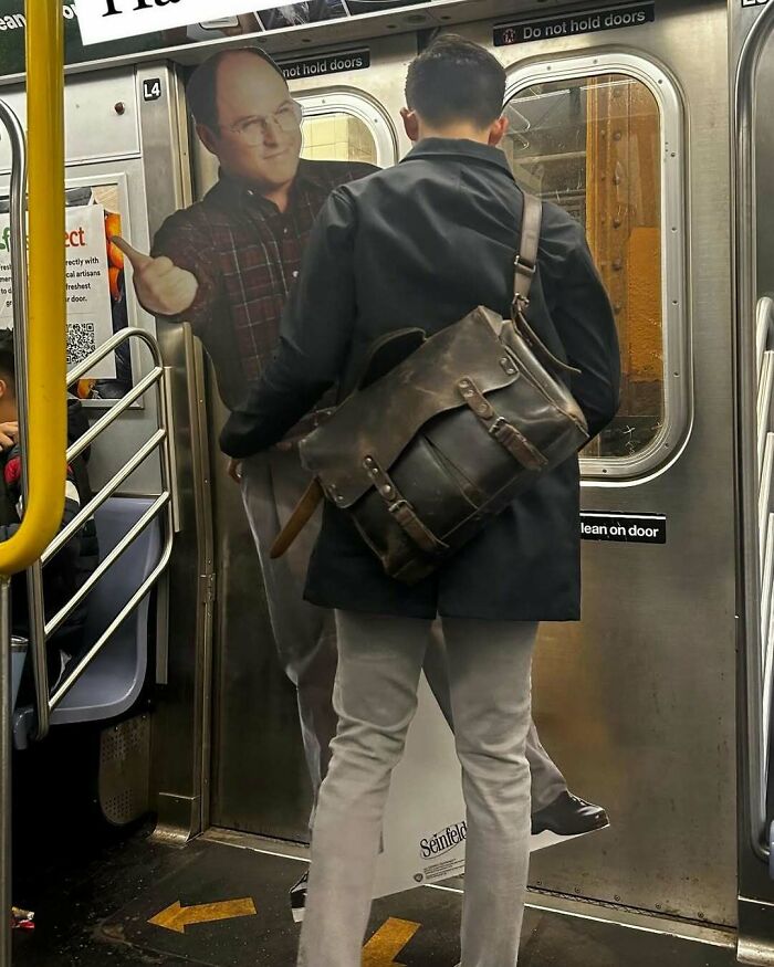 Passenger humorously interacting with a subway door poster displaying a character in a plaid shirt.