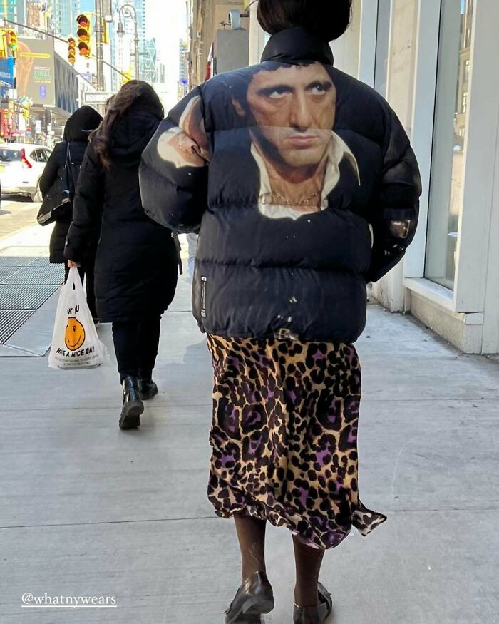 NYC local in a bold jacket with iconic face print and leopard skirt, showcasing unique fashion style.