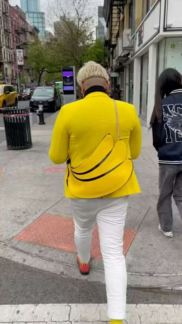 NYC local in a bold yellow outfit with banana design, showcasing unique street fashion on a city sidewalk.