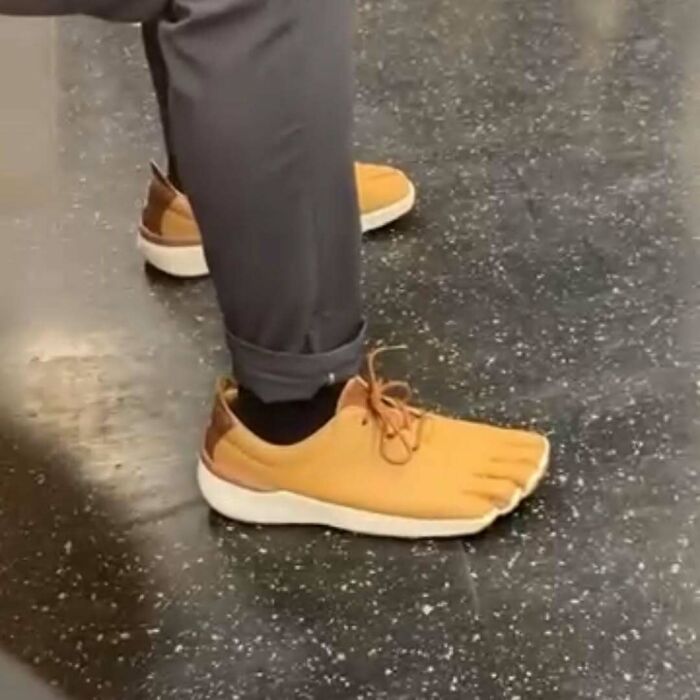 NYC local wearing unique toe-shaped shoes with rolled-up pants, showcasing experimental fashion on a tiled floor.