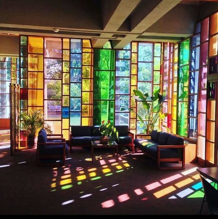 Colorful stained glass windows casting vibrant patterns in a modern interior space, showcasing eclectic design.