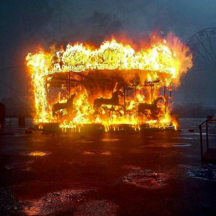 Burning carousel engulfed in flames, creating a bizarre and dramatic scene.