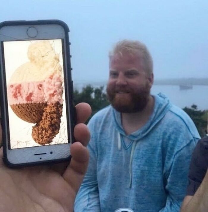 Cracked phone screen shows ice cream overlapping a smiling person, creating a humorous visual effect.