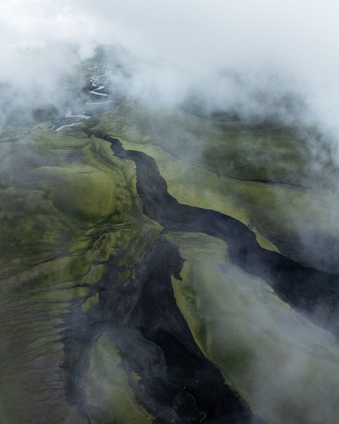 Aerial view of lush, untamed landscape shrouded in mist, showcasing nature's raw beauty.