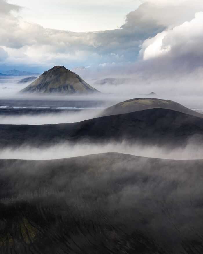 Misty landscape with layered hills and mountains under dramatic clouds, highlighting nature photography by Jeroen Van Nieuwenhove.