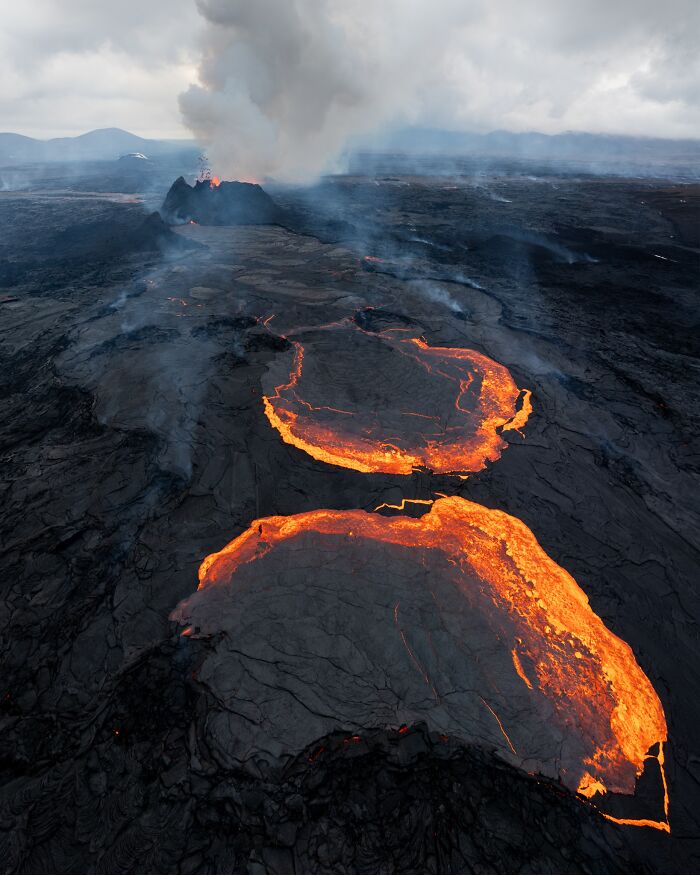 Aerial view of an erupting volcano, glowing lava flows captured in nature photography.