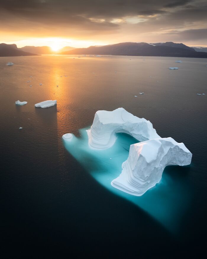 Iceberg in serene water at sunset, showcasing untamed nature.