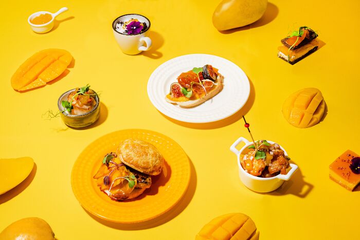 Assorted gourmet dishes artfully arranged on a vibrant yellow background for Tokyo International Foto Awards.