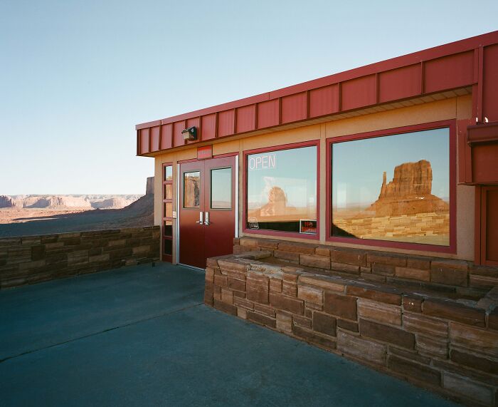 Reflections of desert landscape on glass at an open building, featured in Tokyo International Foto Awards.