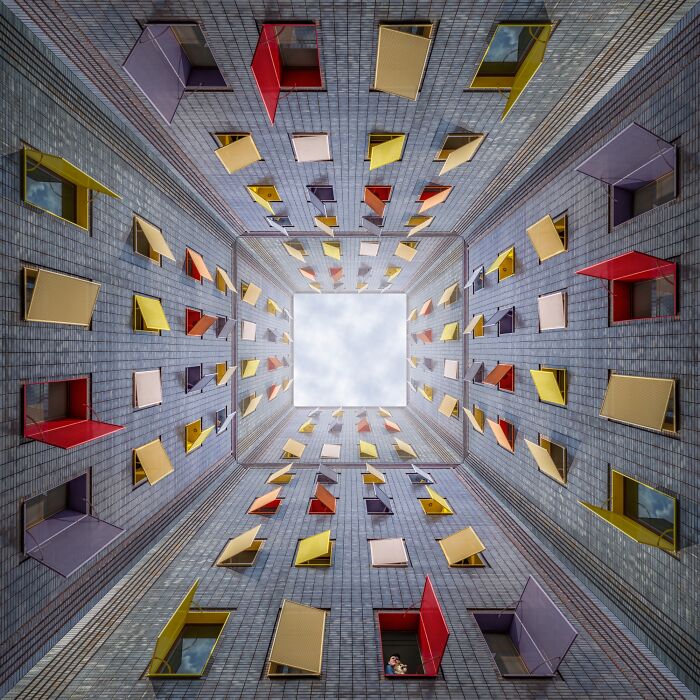 Colorful open windows in a building's courtyard, viewed from below, at Tokyo International Foto Awards 2024.