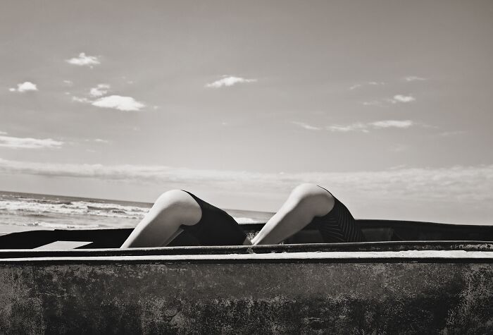 Black and white photo with a person reclining by the ocean, exemplifying Tokyo International Foto Awards creativity.