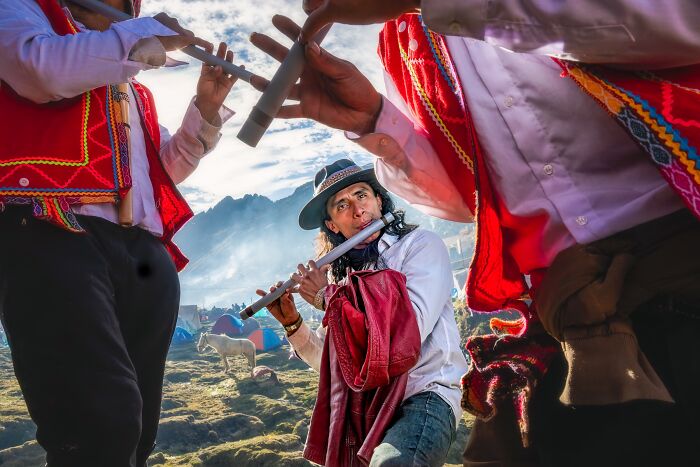 Musicians in vibrant costumes playing flutes outdoors, showcasing cultural heritage at Tokyo International Foto Awards.